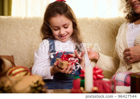 Caucasian delightful cute baby girl rejoices at a Christmas present. Enjoying winter holiday. Magical festive atmosphere at home. Boxing Day. Preparing for Xmas and New Year. Happy carefree childhood Caucasian delightful cute baby girl rejoices at a Christmas present. Enjoying winter holiday. Magical festive atmosphere at home. Boxing Day. Preparing for Xmas and New Year. Happy carefree childhood 96427544