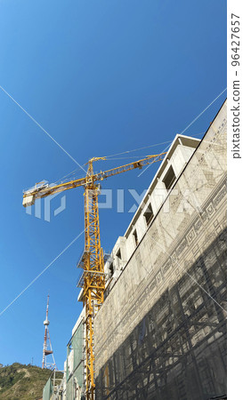 Tower building crane against the blue sky and sun. Construction of new buildings with a crane. Tower crane in Tbilisi, Georgia 96427657