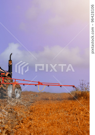 A small agricultural tractor processes the field with herbicides from weeds. 96428106