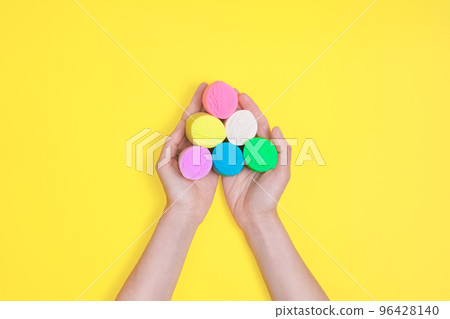 Top view on female hands hold colored modeling clay isolated on yellow background. DIY concept. 96428140