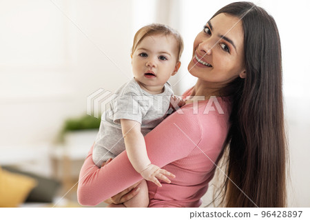 Happiness of motherhood. Portrait of happy mother with cute little baby on her hands looking at camera, copy space Happiness of motherhood. Portrait of happy mother with cute little baby on her hands looking at camera, copy space 96428897