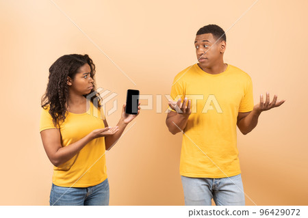 Another life online. Angry african american lady checking her husband cellphone, asking man for explanation Another life online. Angry african american lady checking her husband cellphone, asking man for explanation 96429072
