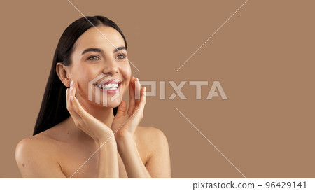 Happy attractive young woman touching her face, copy space Happy attractive young woman touching her face, copy space 96429141