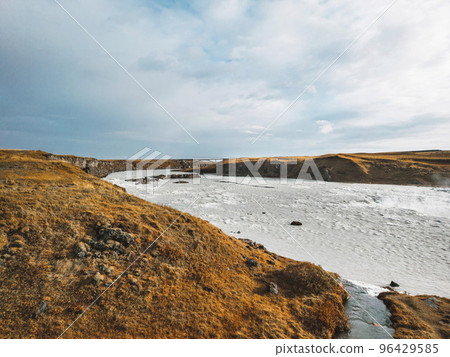 Grass covered hills and bright blue river 96429585