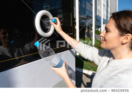 Woman uses a self service machine to receive used plastic bottles  96429956