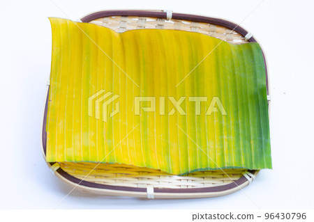 Yellow green banana leaf in bamboo weave plate on white background. 96430796