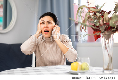 Asian woman swears at someone while talking on a mobile phone Asian woman swears at someone while talking on a mobile phone 96433844