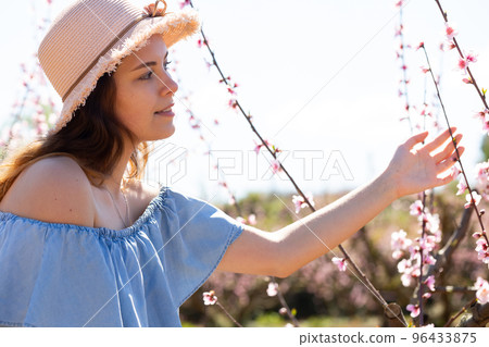 Beautiful blonde girl with long hair in a pink dress in blooming garden. Beautiful blonde girl with long hair in a pink dress in blooming garden. 96433875