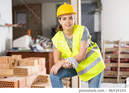 Woman builder posing on indoor construction site 96434103