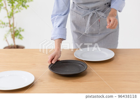 Photo material of a woman arranging dishes on the dining table Photo material of a woman arranging dishes on the dining table 96438118