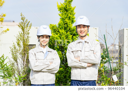 A smiling worker in front of the plants, landscaping industry A smiling worker in front of the plants, landscaping industry 96440104
