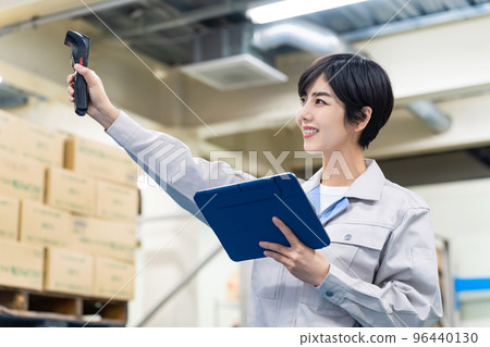 Female employee working with electronic equipment in warehouse 96440130