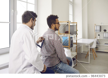 During medical appointment doctor listens to patient's lungs with stethoscope for wheezing. During medical appointment doctor listens to patient's lungs with stethoscope for wheezing. 96443873