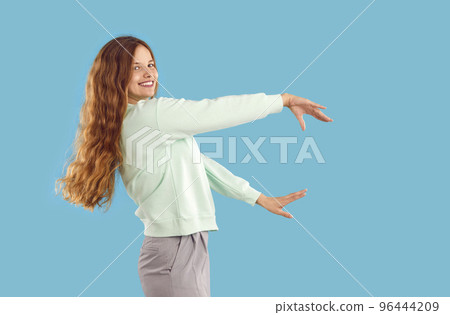 Happy young woman with beautiful long blond hair dancing isolated on blue background Happy young woman with beautiful long blond hair dancing isolated on blue background 96444209