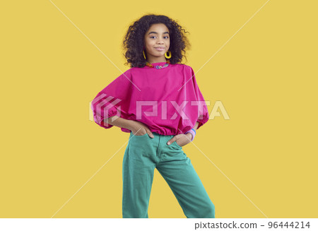 Studio portrait of beautiful stylish dark-skinned curly preteen girl isolated on yellow background. 96444214