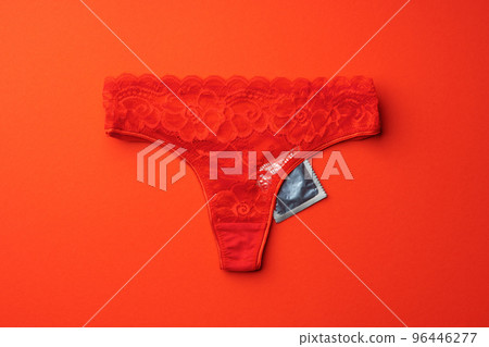 Beautiful women's panties with a condom on a paper background. Safe intimate relationships concept 96446277