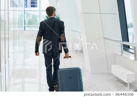 man with luggage walking at the airport . 96446306