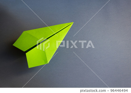Green paper plane origami isolated on a grey background Green paper plane origami isolated on a grey background 96446494