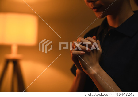 woman hand praying with magic light that flows through on orange bokeh background. woman hand praying with magic light that flows through on orange bokeh background. 96448243