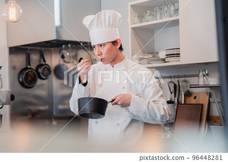 Male chef tasting in the kitchen Male chef tasting in the kitchen 96448281