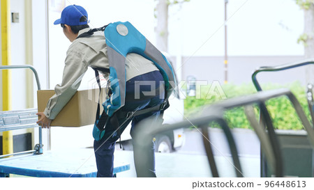 A worker using a power assist suit in a warehouse 96448613