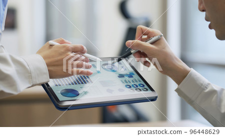 People looking at a tablet screen and talking 96448629