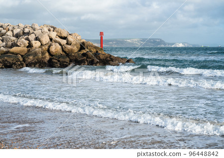 Seaside town of Weymouth in Dorset, United Kingdom. View of the waves in the sea, rocks in the background, selective focus Seaside town of Weymouth in Dorset, United Kingdom. View of the waves in the sea, rocks in the background, selective focus 96448842