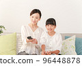 mother and daughter using remote control 96448878