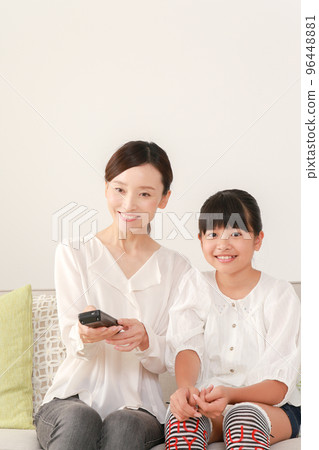 mother and daughter using remote control 96448881