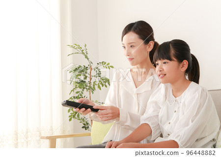 mother and daughter using remote control 96448882