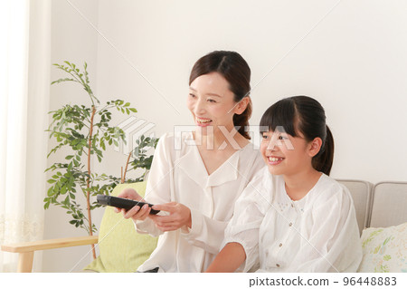 mother and daughter using remote control 96448883