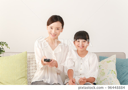 mother and daughter using remote control 96448884