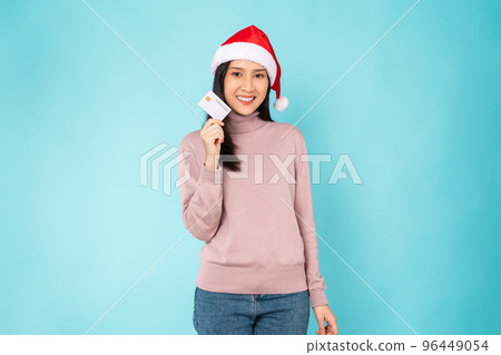 woman wearing red Christmas hat and holding mockup credit card on blue background. woman wearing red Christmas hat and holding mockup credit card on blue background. 96449054
