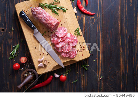 Traditional salami sausage on wooden cutting board with spices Traditional salami sausage on wooden cutting board with spices 96449496