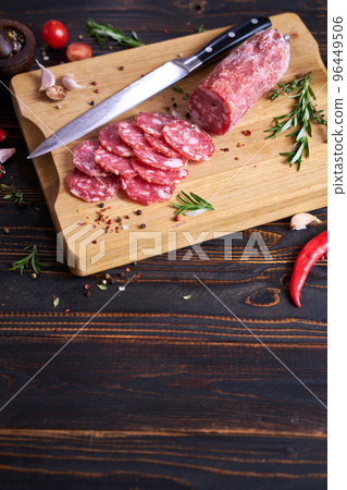 Traditional salami sausage on wooden cutting board with spices 96449506