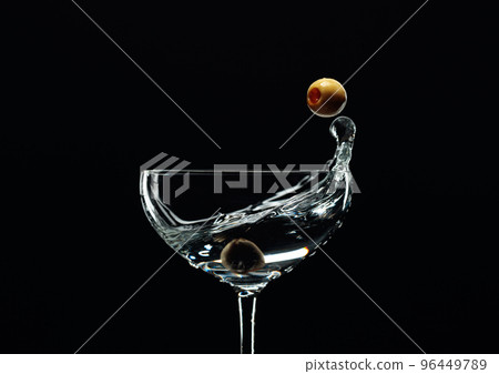 Silhouette of martini with green olives on a black background. 96449789