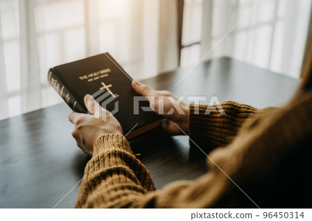 holds bible in hands. Reading the Holy Bible in home. Concept for faith, spirituality and religion. Peace, hope 96450314