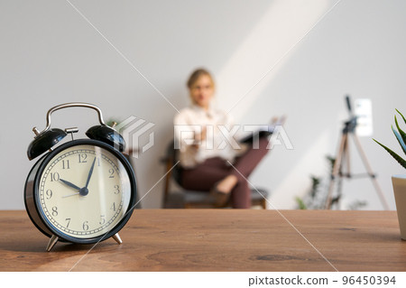 Woman blogger video webinar on background, closeup of alarm clock, selective 96450394