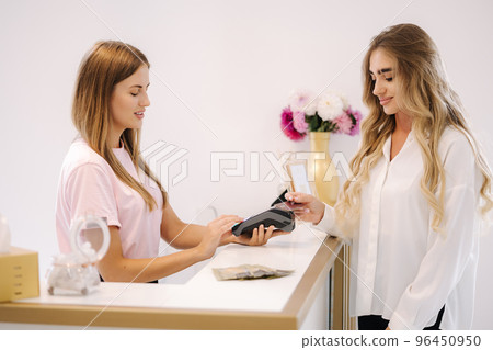 Female customer pay for procedures in beauty studio. Woman using credit cart. Gorgeous lady Female customer pay for procedures in beauty studio. Woman using credit cart. Gorgeous lady 96450950