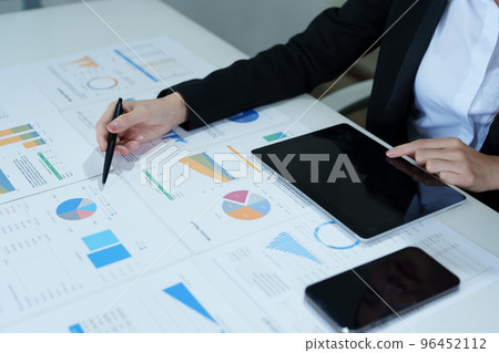 Portrait of a thoughtful Asian businesswoman looking at financial statements and making marketing plans using a tablet computer on her desk. Portrait of a thoughtful Asian businesswoman looking at financial statements and making marketing plans using a tablet computer on her desk. 96452112