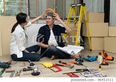 Happy Creative young Asian couple renovating house together and using a blueprint for renovation planning and how to decorate and arrange the furniture on their new living room space Happy Creative young Asian couple renovating house together and using a blueprint for renovation planning and how to decorate and arrange the furniture on their new living room space 96452511