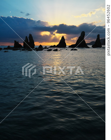 Hashigui-iwa rock bathed in the angel ladder of the rising sun Hashigui-iwa rock bathed in the angel ladder of the rising sun 96452602