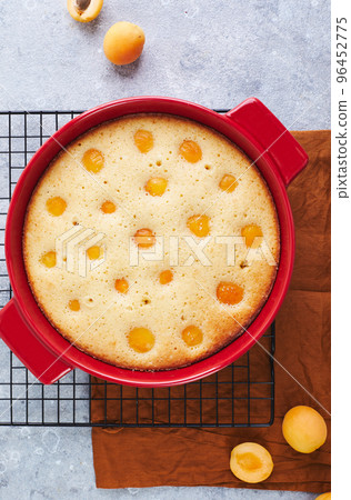 Delicious homemade apricot pie with fresh apricots in red baking dish on gray background. Summer fruit pie. Delicious homemade apricot pie with fresh apricots in red baking dish on gray background. Summer fruit pie. 96452775