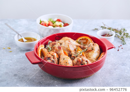 Chicken drumsticks with oranges and thyme baked in red round baking dish Chicken drumsticks with oranges and thyme baked in red round baking dish 96452776