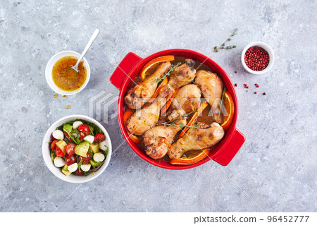 Chicken drumsticks with oranges and thyme baked in red round baking dish Chicken drumsticks with oranges and thyme baked in red round baking dish 96452777