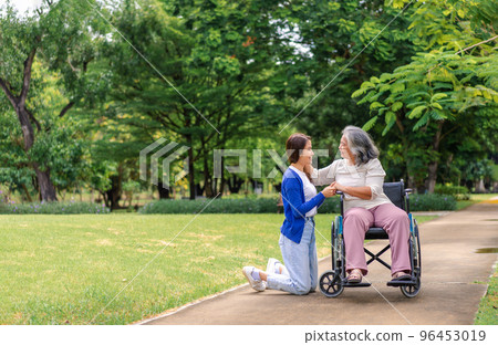 Asian careful caregiver or nurse taking care of the patient in a wheelchair.  Concept of happy retirement with care from a caregiver and Savings and senior health insurance, a Happy family 96453019