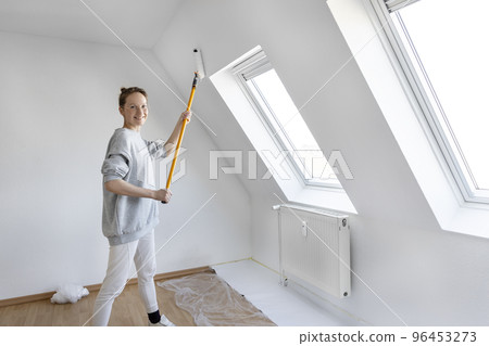 Portrait young adult beautiful single happy woman painting wall paint roller brush white color living room moving new home flat . Female painter decorating interior renovation residential apartment 96453273