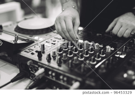 a DJ plays music on a controller at a party. 96453329