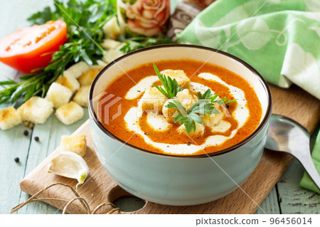 Diet menu. Puree soup tomato with croutons and cream in a bowl on a kitchen wooden table. The concept of healthy eating. 96456014