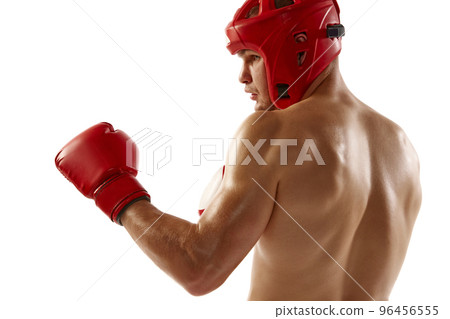 Punch. Young muscled athlete, professional kickboxer in protective helmet and boxing gloves in action isolated on white background. Sport, competition, energy, combat sports 96456555